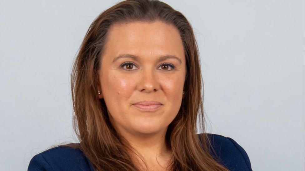 Woman with long brown hair wearing a blue jacket