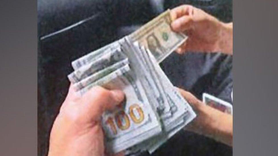 A wad of American cash held by a law enforcement official.