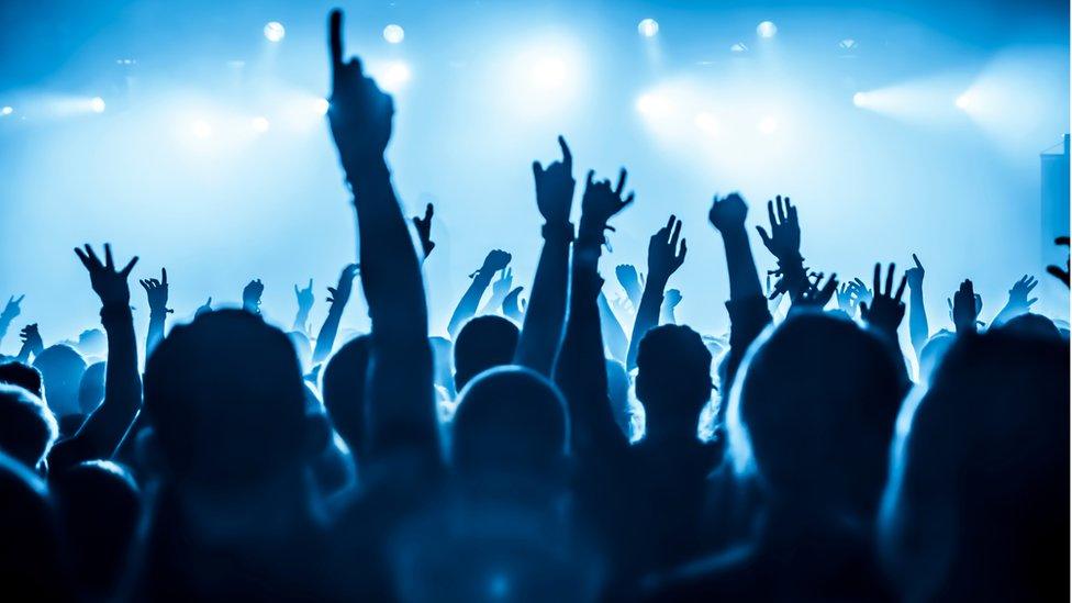 Festival revellers dancing in front of a stage