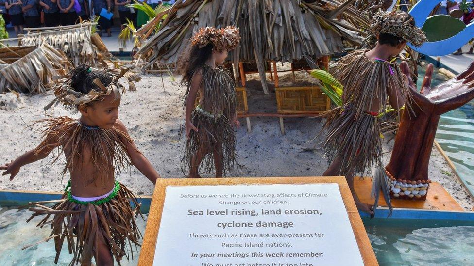 Tuvalu children stand next to climate change messages as leaders arrive at the forum