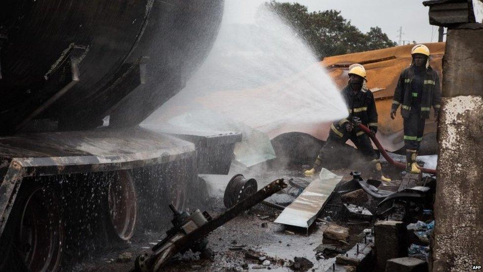 A fireman sprays water after a gas tanker caught fire, triggering explosions at two fuel stations