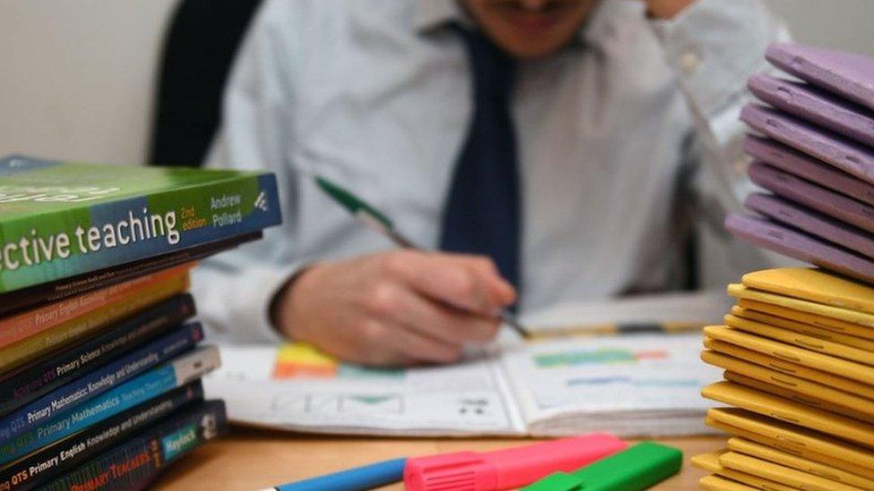 Teacher marking, surrounded by books