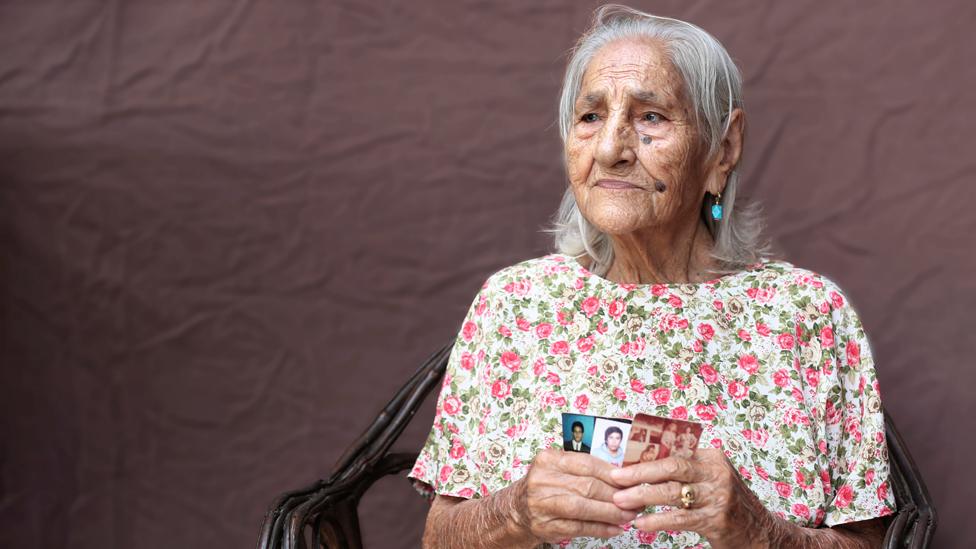 María Teresa Jimenez holds up photographs of her children