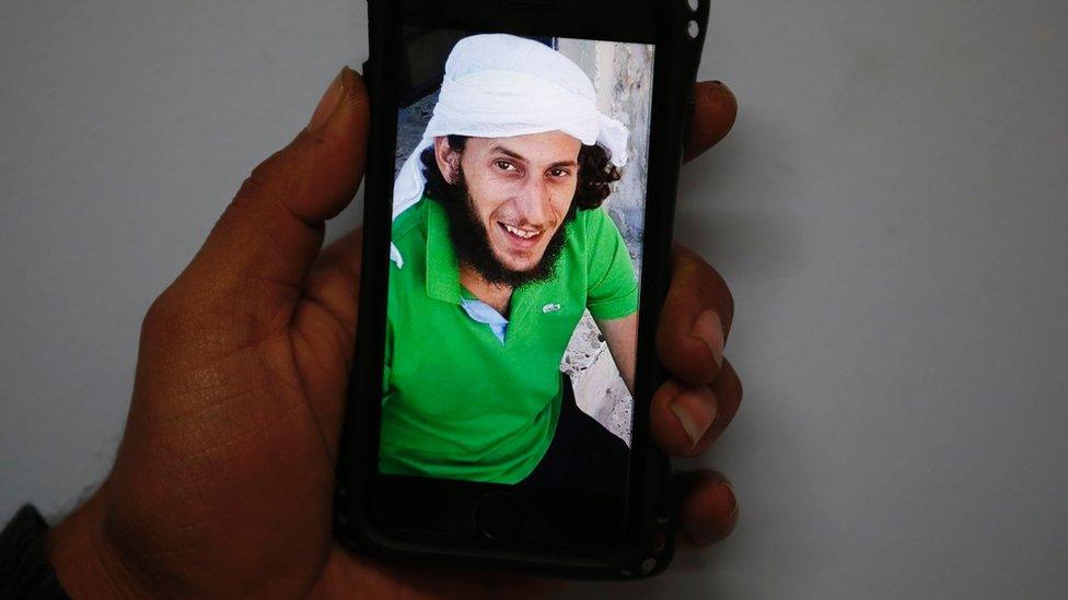 A picture taken on January 8, 2017 in Jerusalem shows the hand of a Palestinian man holding a mobile phone showing a photo of Fadi Al-Qanbar
