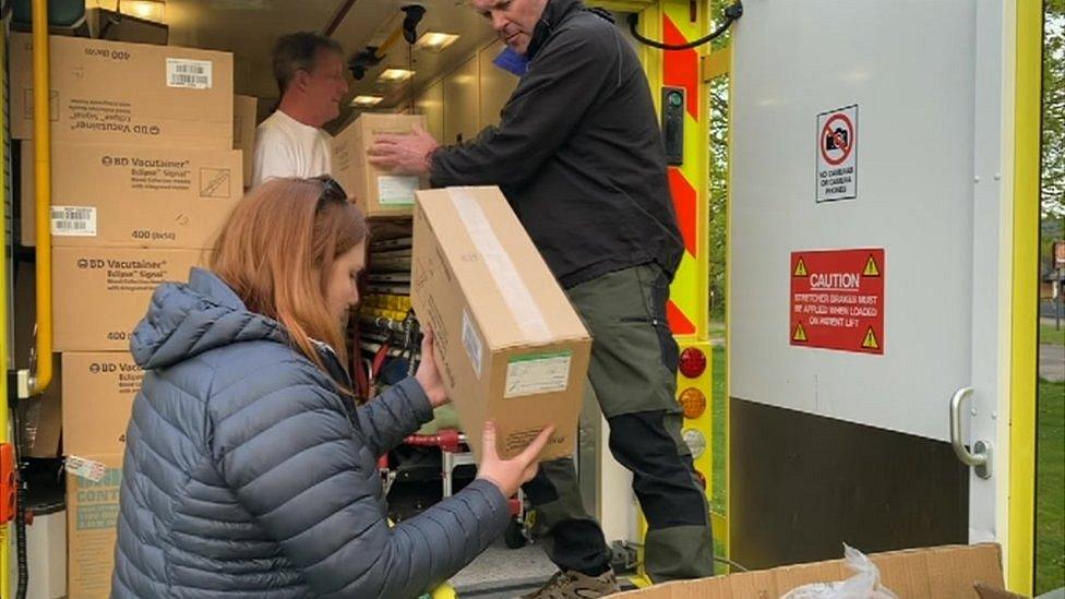 People loading boxes into an ambulance