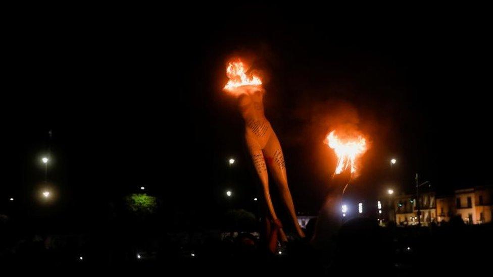 A person carries a burning mannequin during a protest in Mexico City