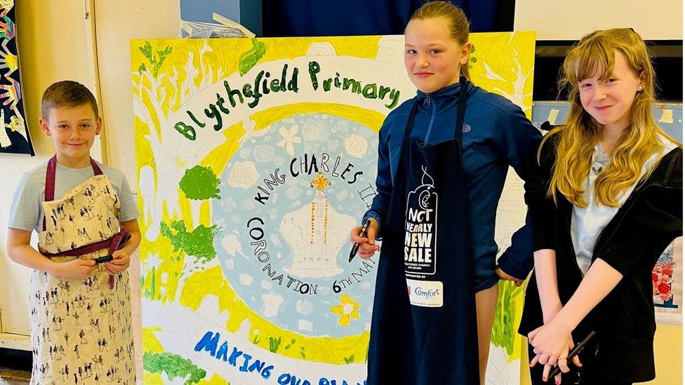 School children stand with an artwork to mark the Coronation