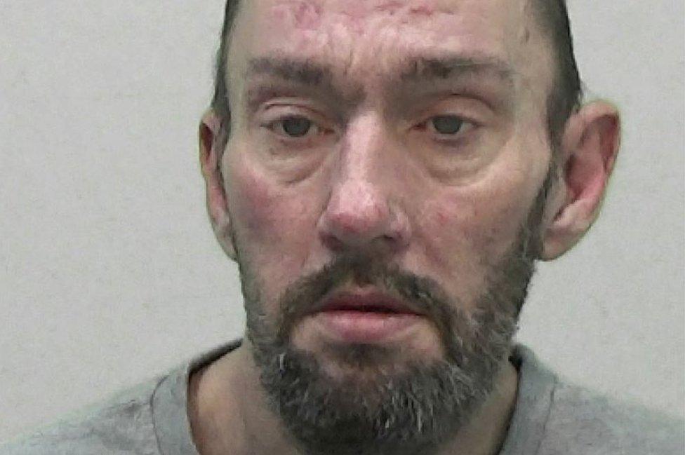 Mugshot of a man with a dark beard