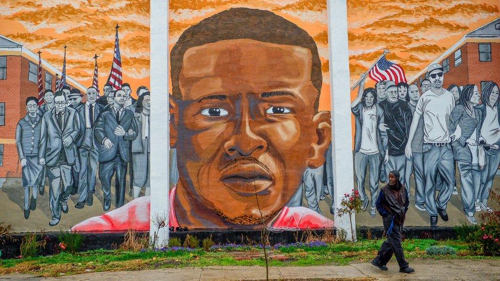 A man, who declined to offer his name, walks past a mural of Freddie Gray in the Sandtown-Winchester neighborhood of Baltimore, December 17, 2015.