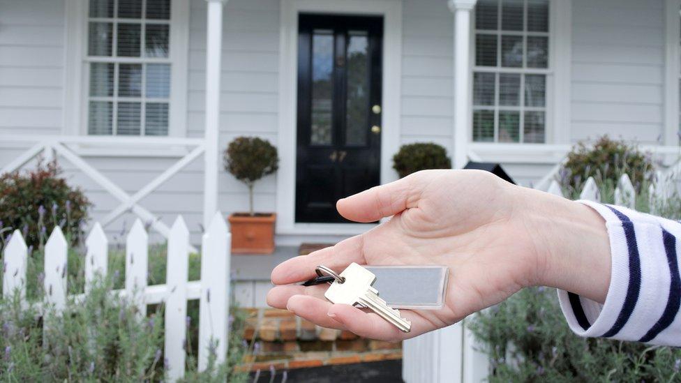 A woman holds a key outside a traditional villa house in Auckland, New Zealand. File photo