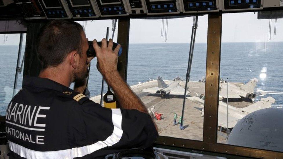 A lieutenant observes Rafale fighter jet movements from the command post aboard France's Charles de Gaulle