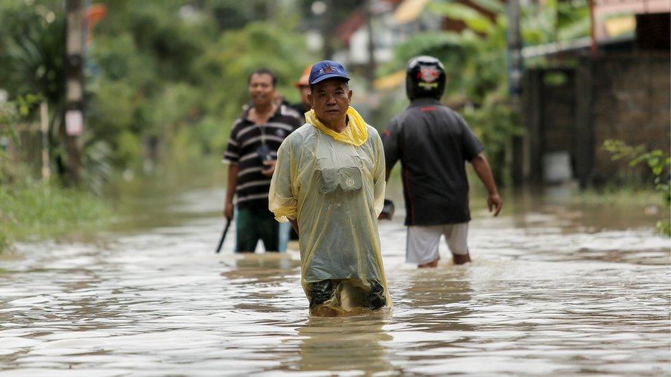 People walk in a flooded street at Muang district in Nakhon Si Thammarat Province, southern Thailand, 6 January 2017