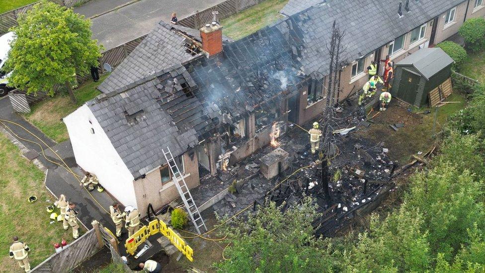 Image of firefighters at work on badly burned houses