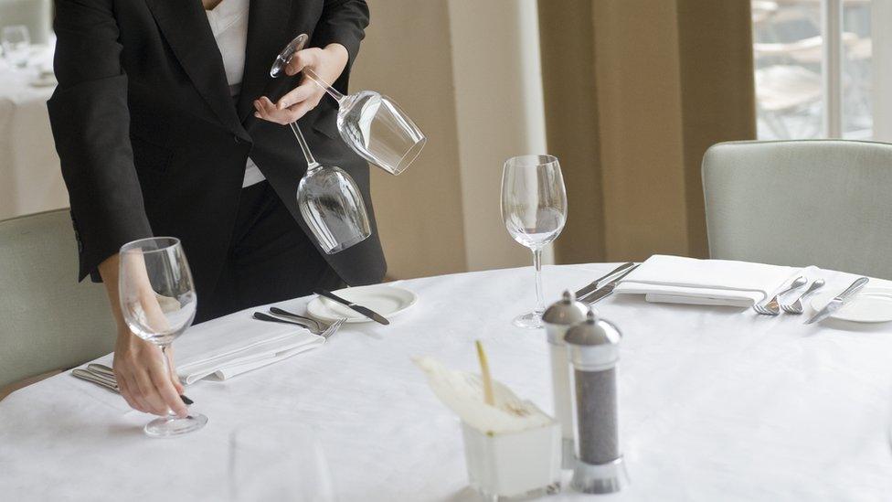 Woman setting table in restaurant