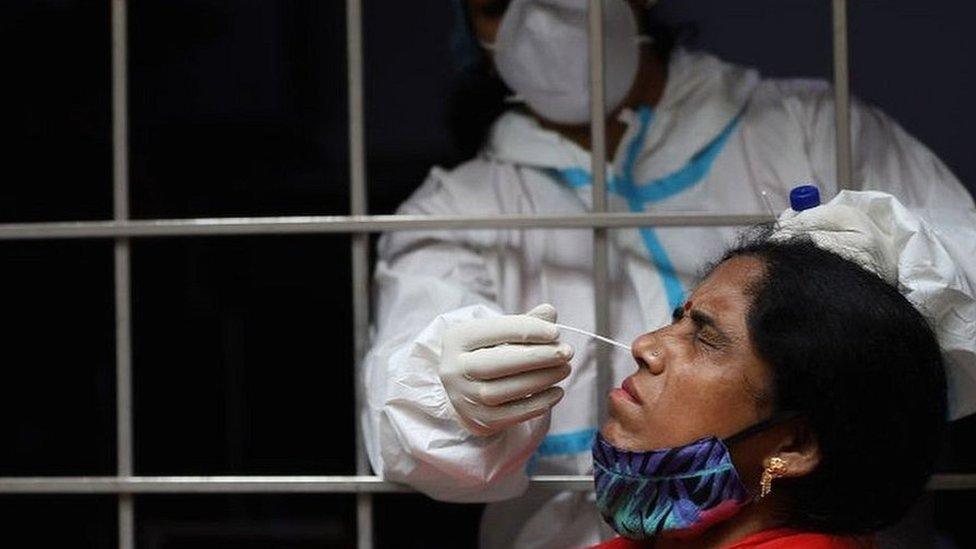 A health worker collects a swab sample from a woman in Delhi