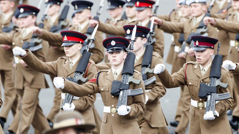 Junior soldiers in a row performing in a parade while carrying rifles