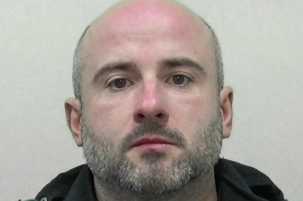 Mugshot of a man with a bald head and grey beard