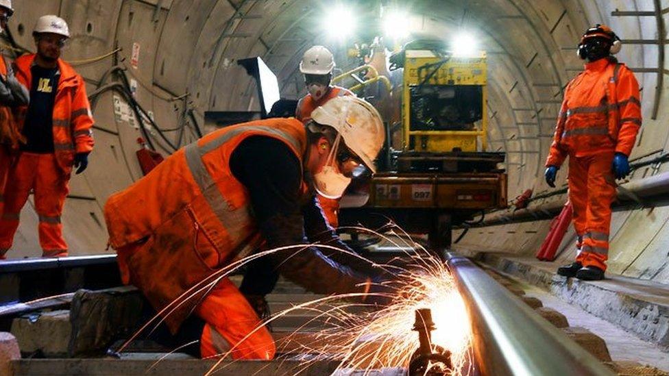 Construction workers work on a section of train track inside a Crossrail tunnel, beneath Stepney in east London in 2016