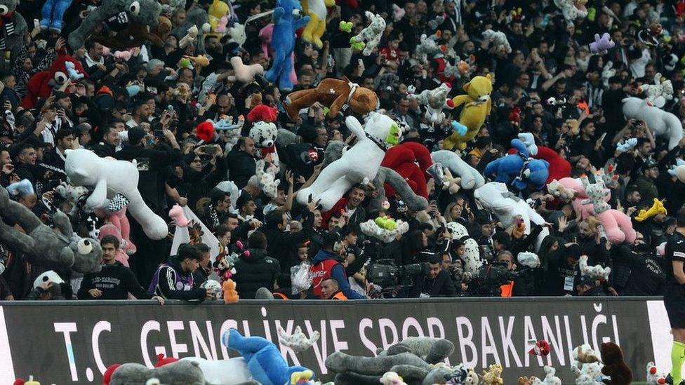 Fans of Besiktas throw Teddy bears onto the field in support for the earthquake victim children