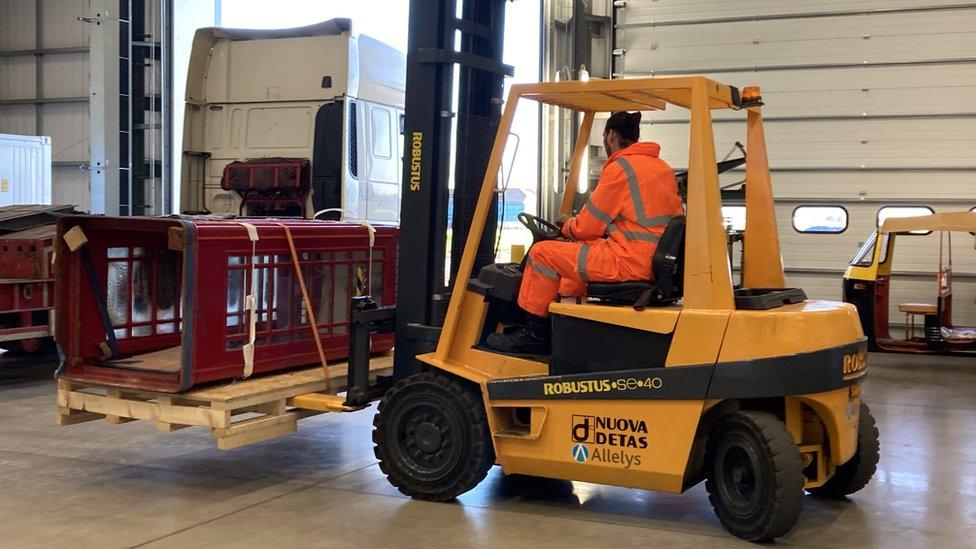 A forklift truck holds up a classic red telephone box.