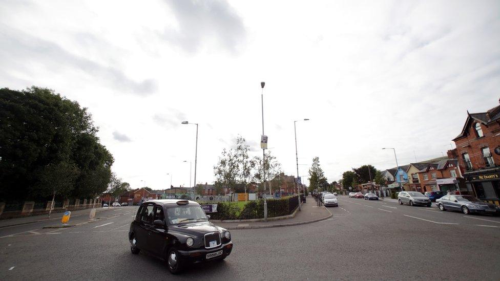 Black taxi passes former site of Andersonstown Barracks