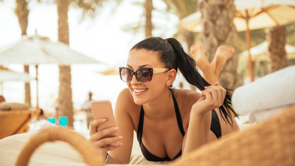 Stock image of a woman using her phone on holiday