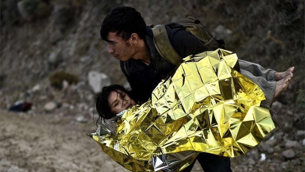 A man carries a girl as refugees and migrants arrive at the Greek island of Lesbos after crossing the Aegean sea from Turkey on 1 October 2015.