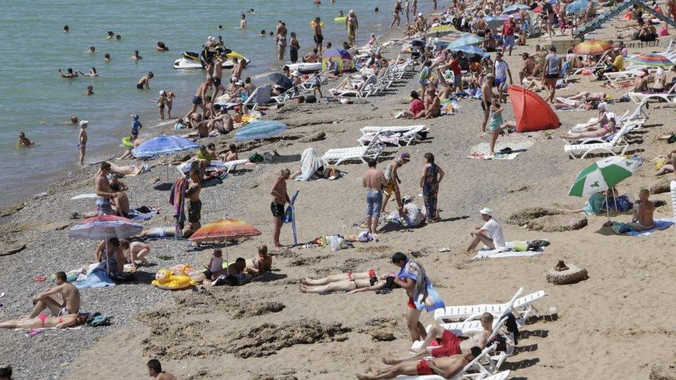 Tourists sunbathing on a sandy beach in Crimea