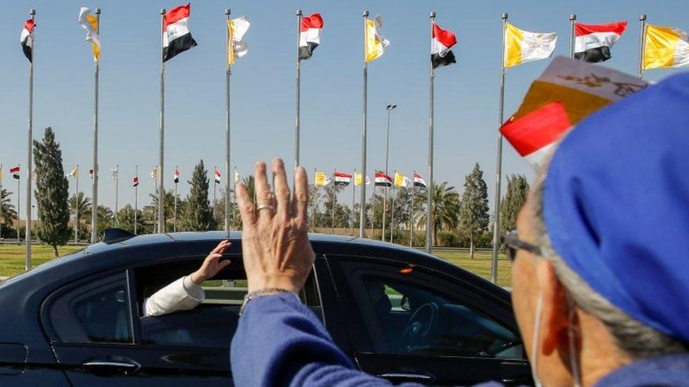 Pope Francis waves as his convoy heads into Baghdad from the airport