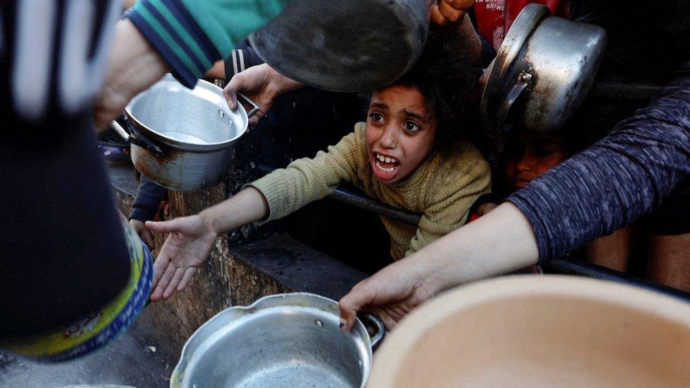 Palestinians wait to receive food in Rafah, in the southern Gaza Strip (13 March 2024)