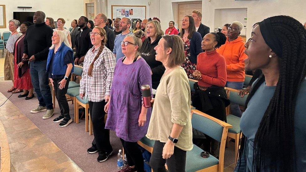 Dozens of members of Bristol's Renewal Choir stand and sing together in their rehearsal hall in Knowle West