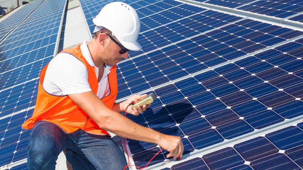 Technician checking solar panels on a roof