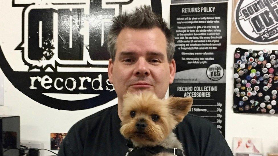 Tom Butchart and his dog in front of Sound It Out signage