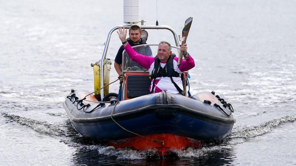 Baton bearer Jason Watkin travels by speed boat as he carries the baton on a visit to the River Tees Watersports Centre