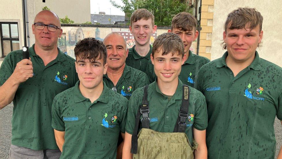 James and his teammates wearing their green team polo shirts pose for a group photo in the rain