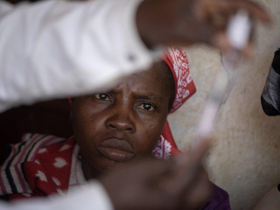 A woman looks a syringe containing a vaccine