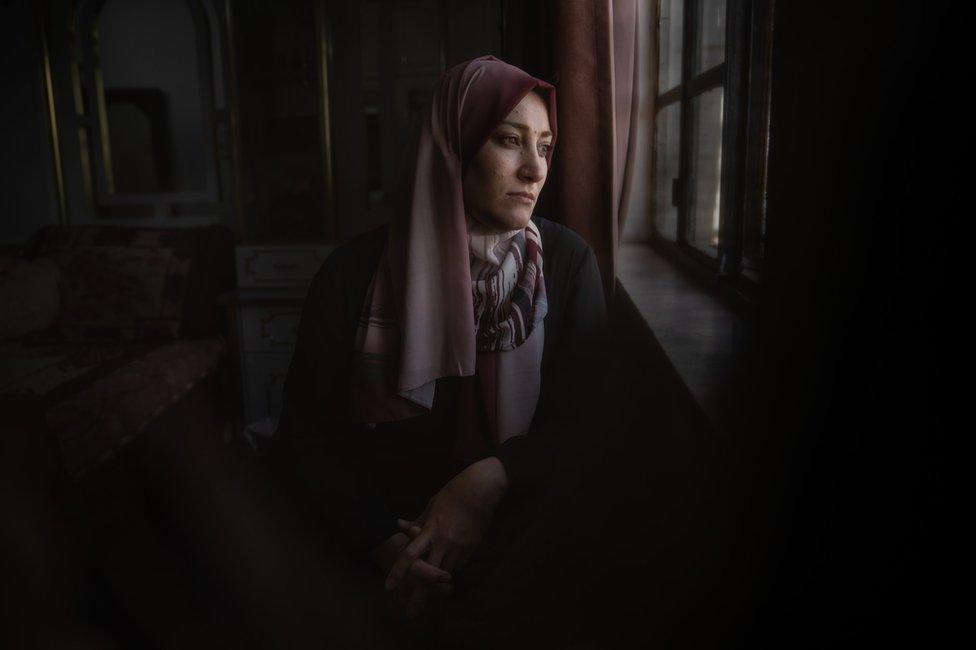 Areej Jabari, a resident of H2, looks out of her window onto the street, which she can no longer use freely.