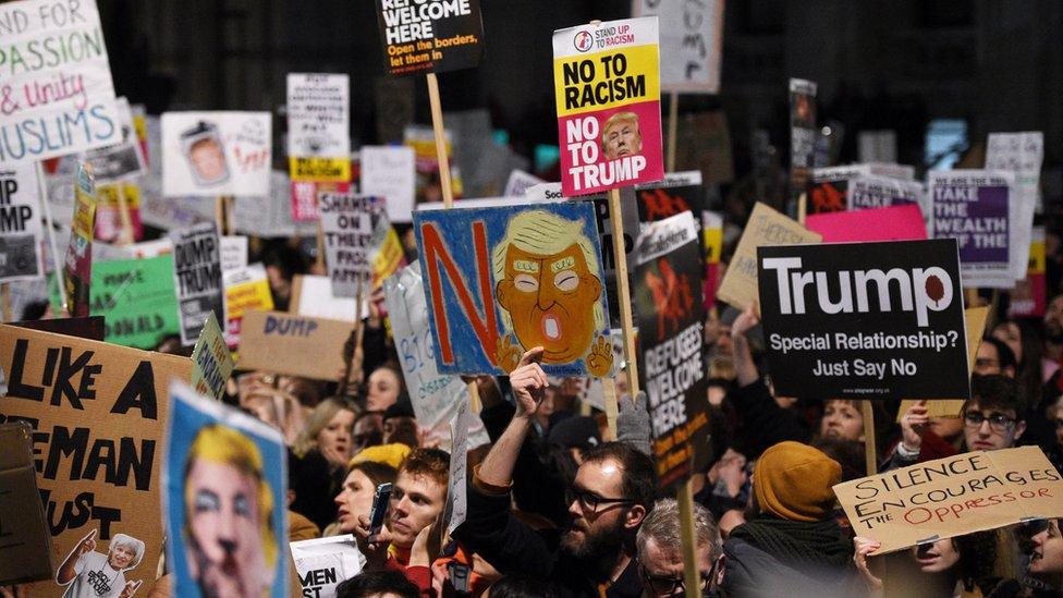 Protesters hold banners during a demonstration outside 10 Downing Street in London (30 January 2017)