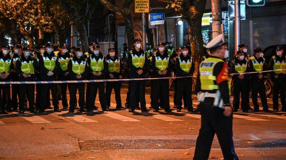 Police block people protesting from a road in Shanghai.