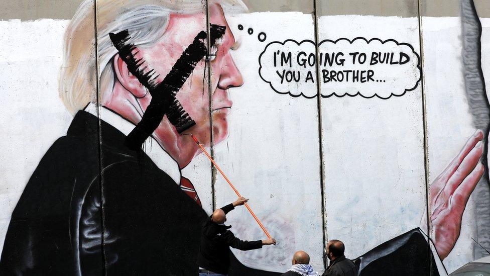 Palestinians paint an X over the face of a picture of Donald Trump on the Israeli separation wall in Bethlehem, West Bank, on 7 December 2017