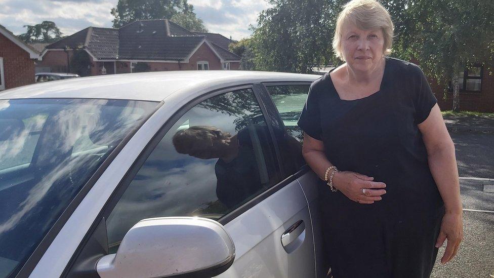 June Leatham, 72, in front of her car