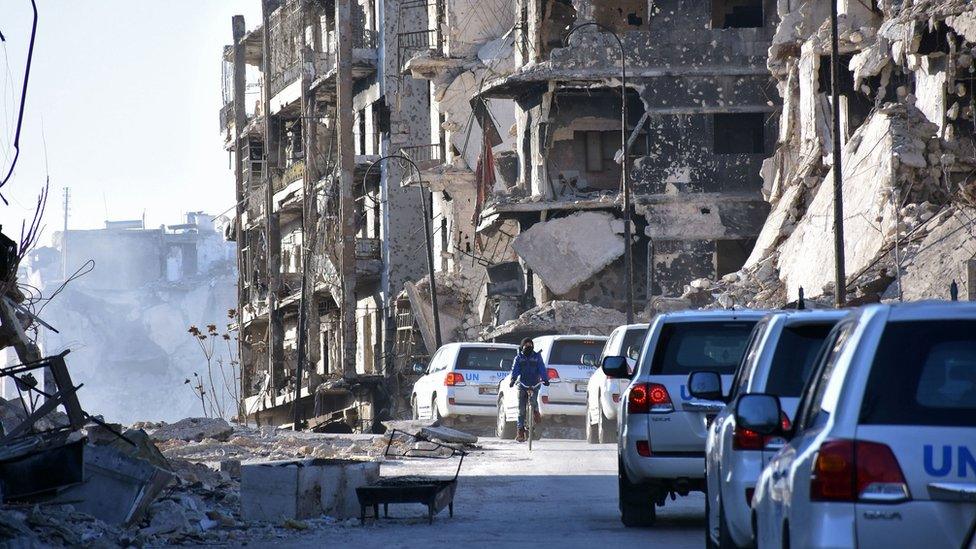 A UN convoy drives past damaged buildings in the eastern neighbourhoods of Syria's second city of Aleppo, on February 1, 2017