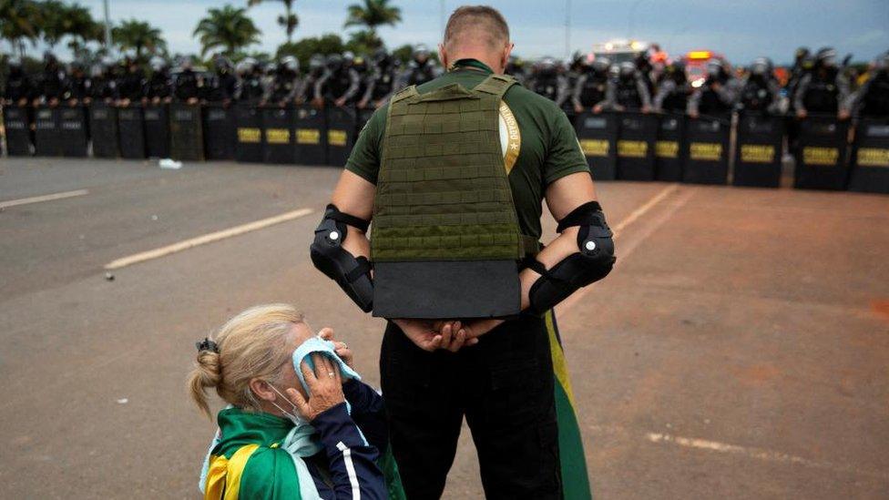 One Bolsonaro supporter shields another in Brasilia on Sunday