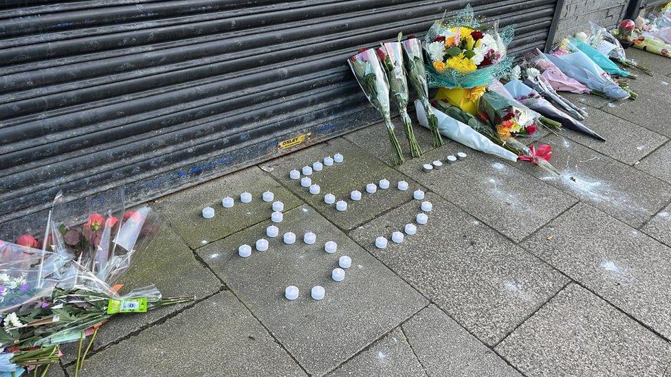 Floral tributes and candles laid out in the number "35"