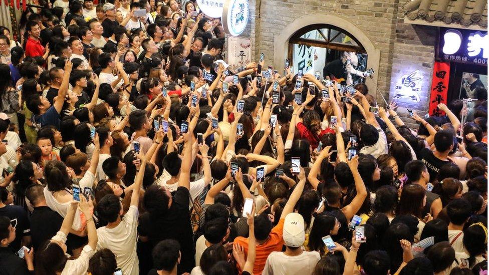 Fans record videos on their smartphones as boy band Modern Brothers performs during a live webcast at Andong Old Street on June 30, 2018 in Dandong, Liaoning Province of China.