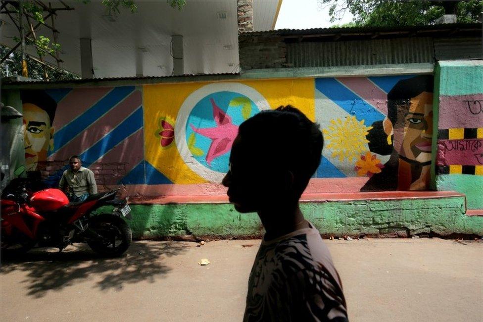 Indian commuters walk past a painted wall at Sonagachi red light district in Kolkata