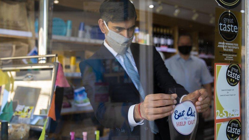 Then-Chancellor Rishi Sunak applies a "Eat Out to Help Out" sticker to a window of a business in Northallerton