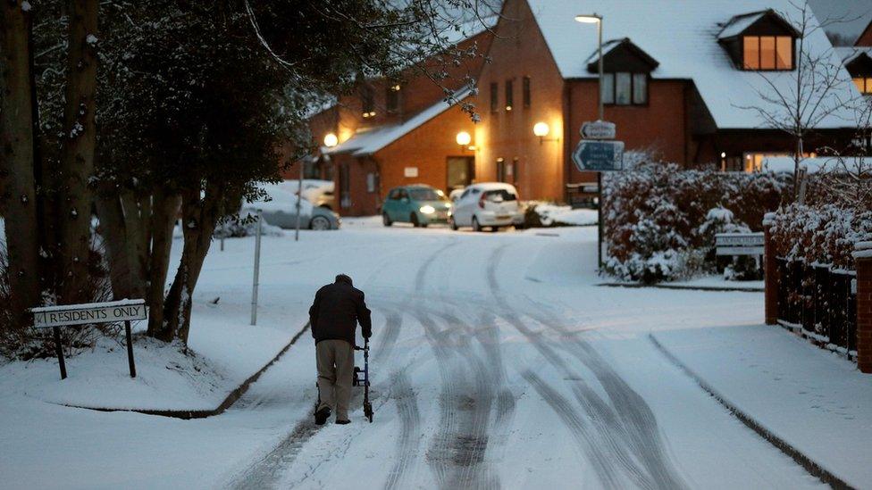 An elderly resident makes his way up a snow covered road