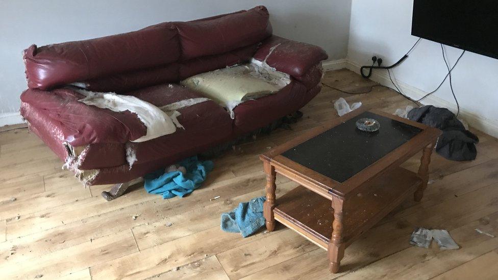 Wrecked burgundy leather sofa in flat