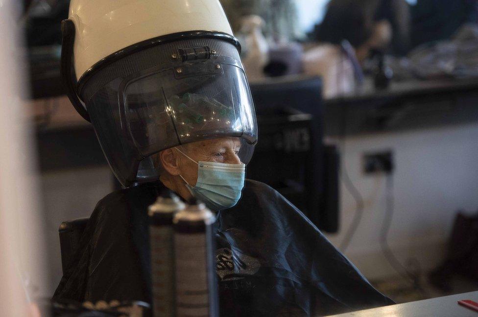 An elderly woman wearing a mask in a hair salon